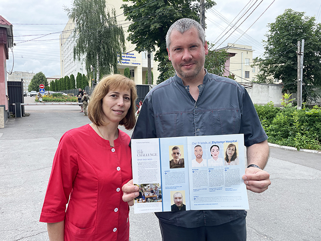 Nurse in magenta scrubs and surgeon in Ukraine hold a copy of Working Nurse