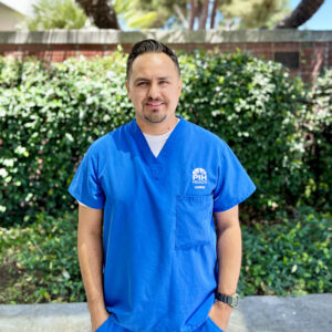 Male nurse in blue scrubs posing outside