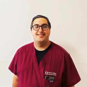 Male nurse in purple scrubs smiling