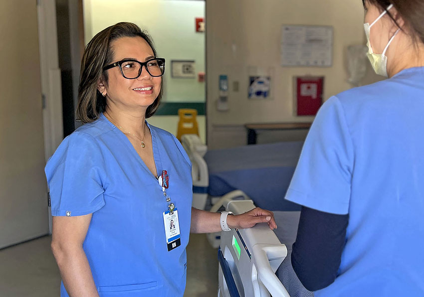 Sheila Chua wearing blue scrubs chatting with another nurse in blue scrubs